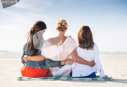 Image of group of young women hugging on beach