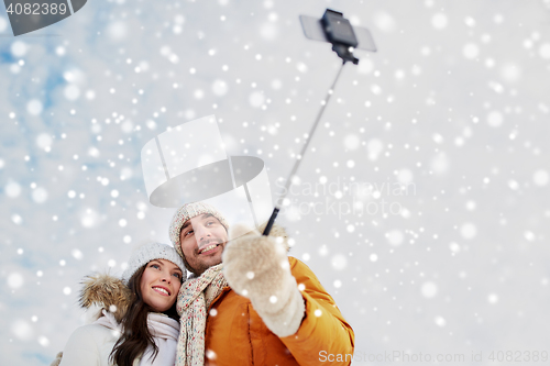 Image of happy couple taking selfie by smartphone in winter