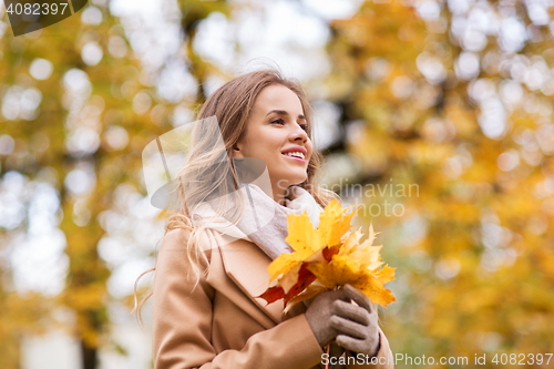 Image of beautiful woman with maple leaves in autumn park