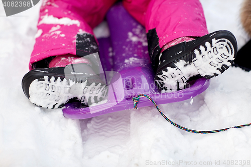 Image of close up of kids feet in winter boots on sled