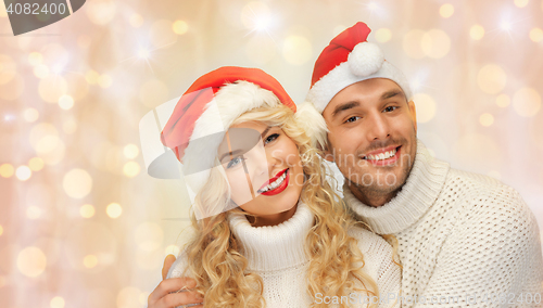Image of happy family couple in sweaters and santa hats