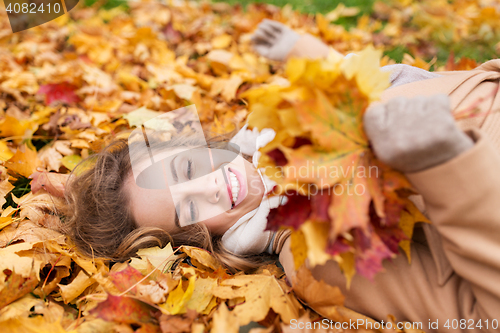 Image of beautiful happy woman lying on autumn leaves