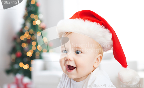 Image of baby boy in christmas santa hat over blue lights