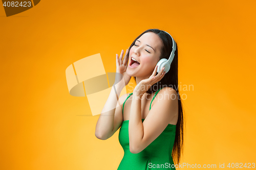 Image of The cute cheerful girl on orange background