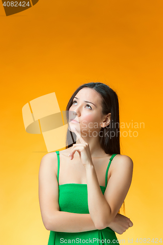 Image of The thinking Chinese girl on yellow background