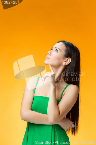 Image of The thinking Chinese girl on yellow background