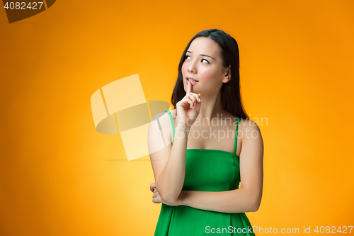 Image of The thinking Chinese girl on yellow background