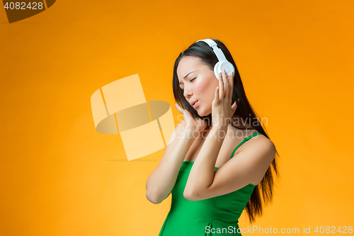 Image of The cute cheerful girl on orange background