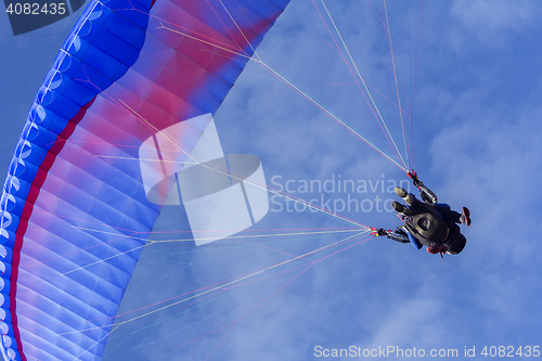 Image of Tandem Paragliding on background of blue summer sky and white cl