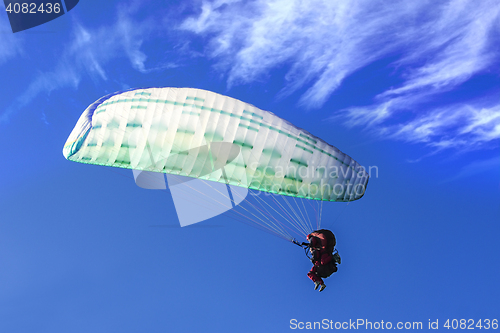 Image of Tandem Paragliding on background of blue summer sky and white cl