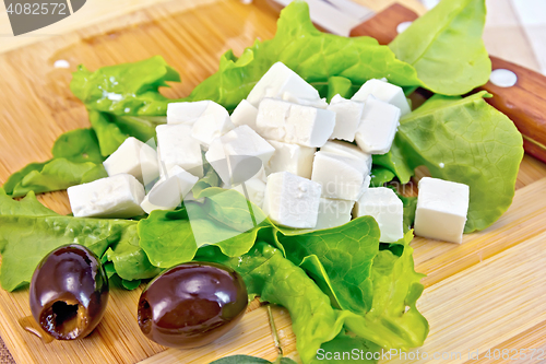 Image of Feta with olives and green lettuce on board