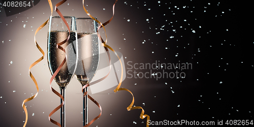 Image of Glasses with fizzing champagne, decorative ribbons and snow flakes closeup