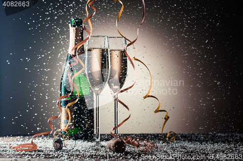 Image of Open bottle of champagne and two filled glasses, festive composition