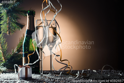 Image of Champagne bottle, full wineglasses, gift box and fir-tree branch