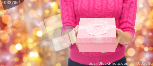 Image of close up of woman in pink sweater holding gift box