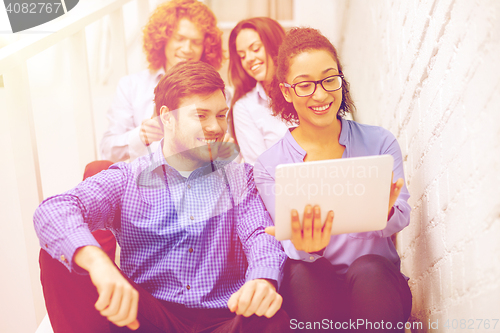 Image of team with tablet pc computer sitting on staircase
