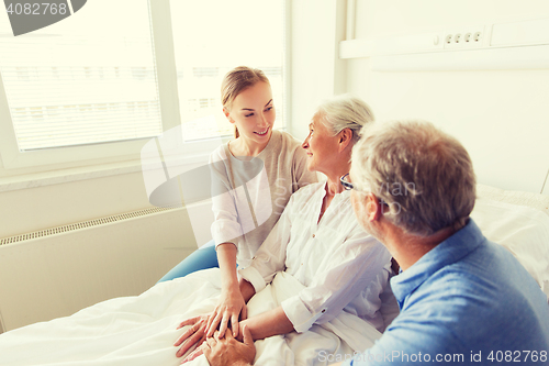 Image of happy family visiting senior woman at hospital