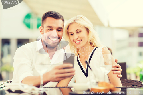 Image of happy couple taking selfie with smatphone at cafe
