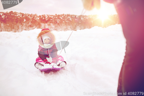 Image of parent carrying happy little kid on sled in winter