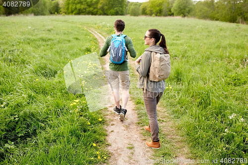 Image of happy couple with backpacks hiking outdoors