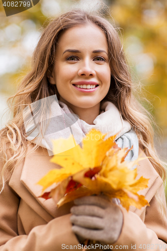 Image of beautiful woman with maple leaves in autumn park