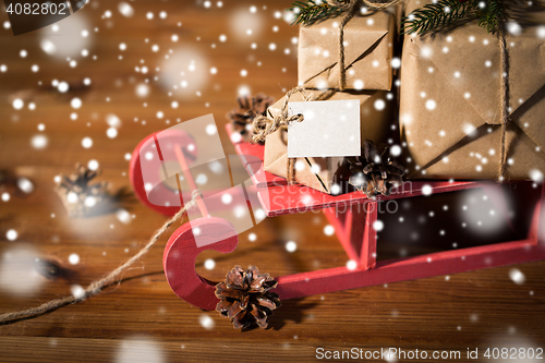 Image of close up of christmas gifts with note on sleigh