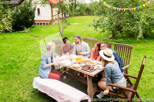 Image of happy friends having dinner at summer garden party