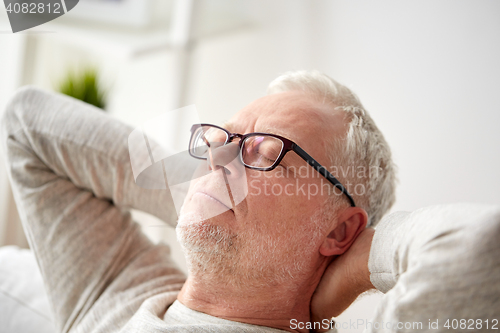 Image of senior man in glasses relaxing on sofa