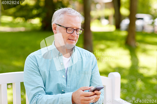 Image of happy senior man texting on smartphone at summer