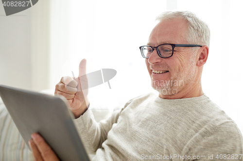 Image of senior man having video call on tablet pc at home