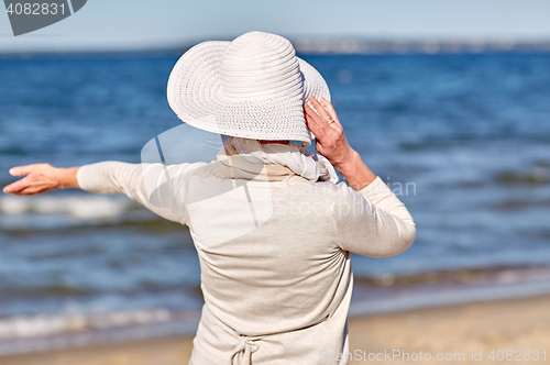 Image of happy senior woman in sun hat on summer beach