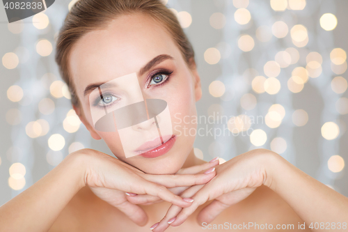 Image of beautiful young woman face and hands over lights