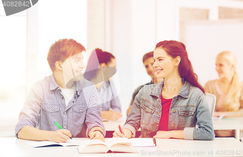 Image of two teenagers with notebooks and book at school