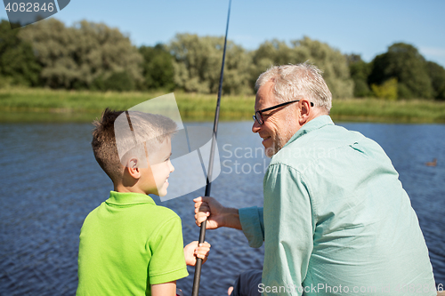 Image of grandfather and grandson fishing on river berth