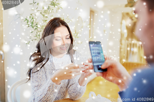 Image of happy couple with smartphones drinking tea at cafe