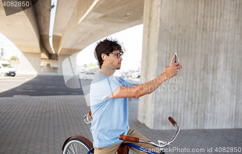 Image of man with smartphone and earphones on bicycle