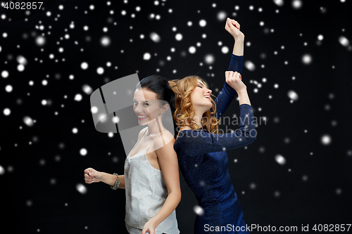 Image of happy young women dancing over snow