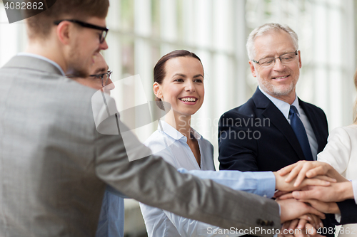 Image of business people putting hands on top in office