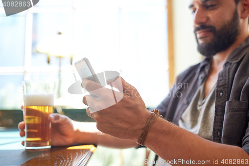 Image of close up of man with smartphone and beer at pub