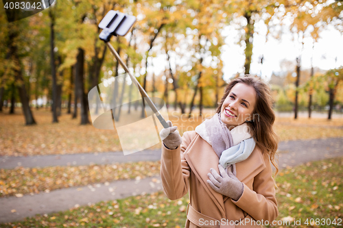 Image of woman taking selfie by smartphone in autumn park