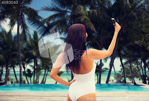 Image of young woman taking selfie with smartphone on beach