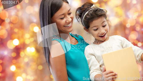 Image of happy mother and girl with gift box over lights