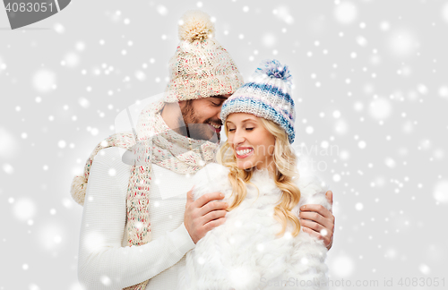 Image of smiling couple in winter clothes hugging over snow