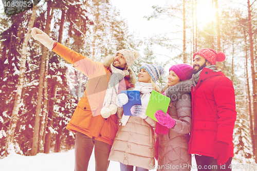 Image of smiling friends with tablet pc in winter forest