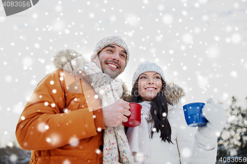 Image of happy couple with tea cups over winter landscape