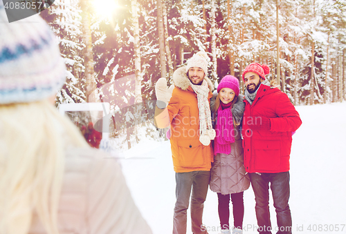 Image of smiling friends with tablet pc in winter forest