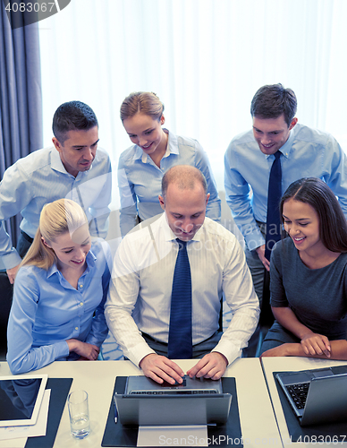 Image of smiling business people with laptop in office