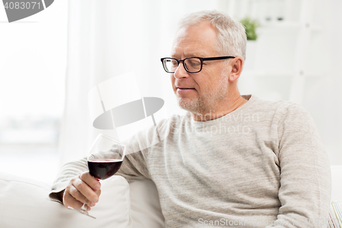 Image of senior man drinking red wine from glass at home