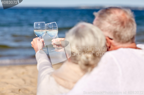 Image of happy senior couple drinking wine on summer beach