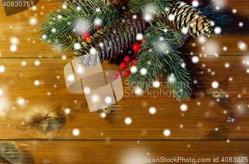 Image of close up of fir branch with cones on wooden table